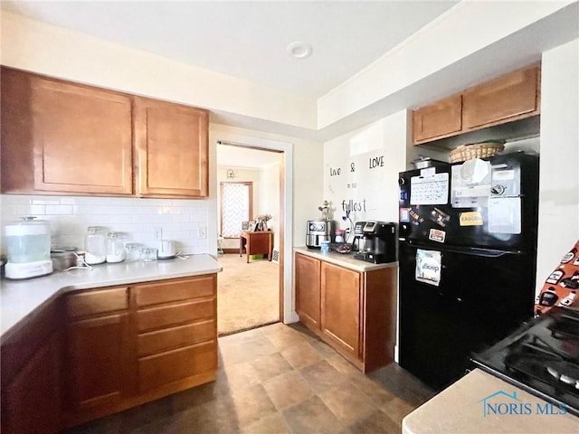 kitchen with black refrigerator and tasteful backsplash