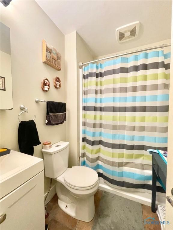 bathroom with vanity, tile patterned flooring, toilet, and walk in shower