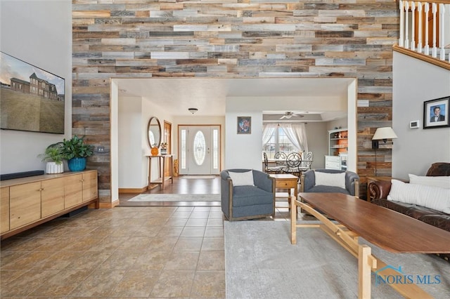 living room featuring ceiling fan, tile patterned floors, and wood walls