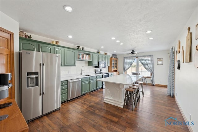 kitchen featuring sink, a breakfast bar area, green cabinets, stainless steel appliances, and a center island