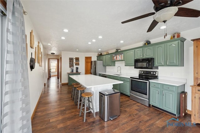 kitchen featuring sink, a breakfast bar, green cabinets, appliances with stainless steel finishes, and a center island