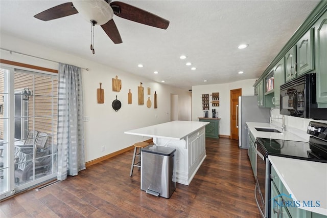 kitchen featuring dark hardwood / wood-style flooring, green cabinets, a kitchen island, electric stove, and ceiling fan