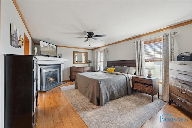 bedroom with multiple windows, ornamental molding, hardwood / wood-style flooring, and ceiling fan