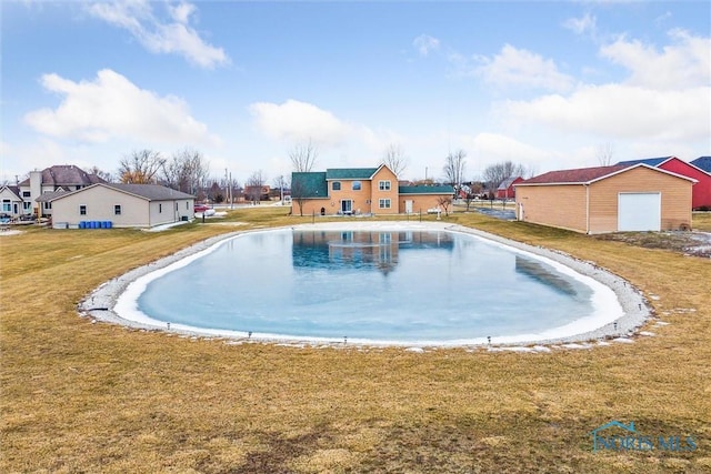 view of swimming pool featuring a garage, an outdoor structure, and a lawn