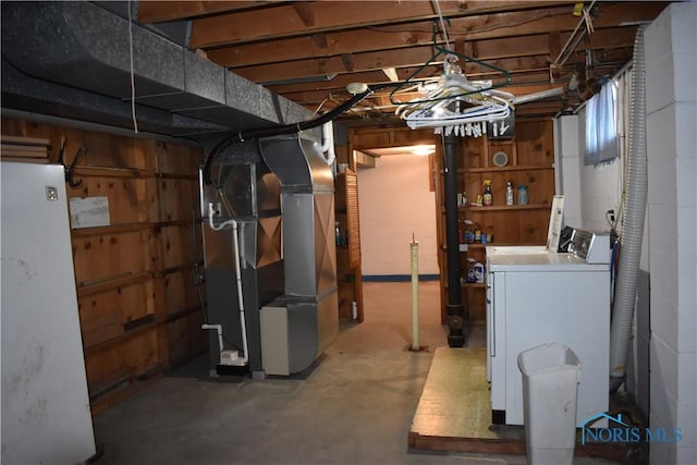 basement with heating unit, washing machine and clothes dryer, and refrigerator