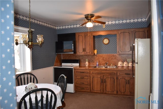 kitchen featuring sink, ceiling fan with notable chandelier, range with electric cooktop, and white refrigerator