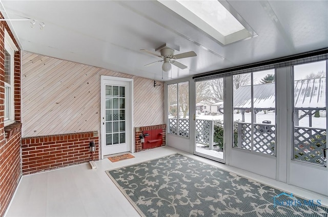 unfurnished sunroom featuring ceiling fan and a skylight