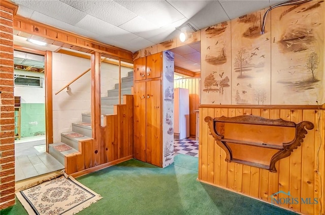 basement featuring wooden walls and dark carpet