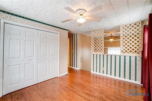 unfurnished bedroom featuring ceiling fan, wood-type flooring, and a closet