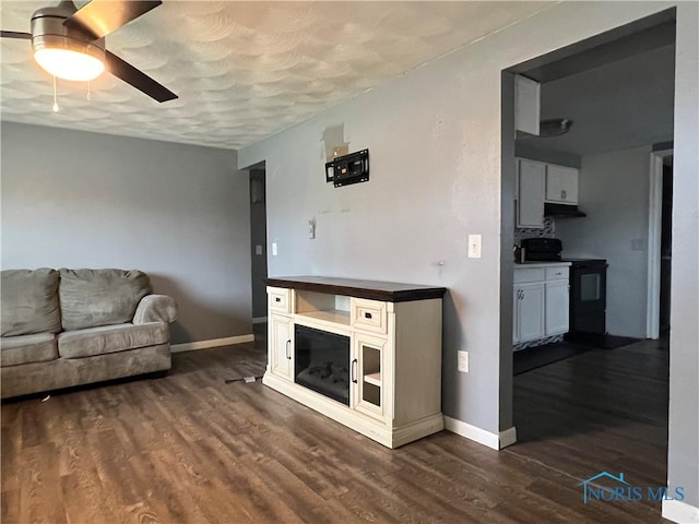 unfurnished living room featuring dark wood-type flooring and ceiling fan