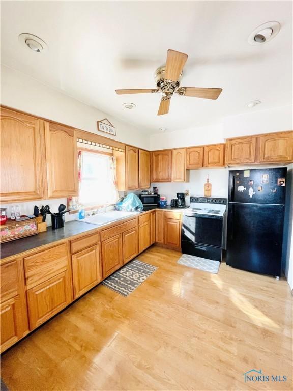 kitchen featuring sink, electric range oven, black refrigerator, ceiling fan, and light hardwood / wood-style floors