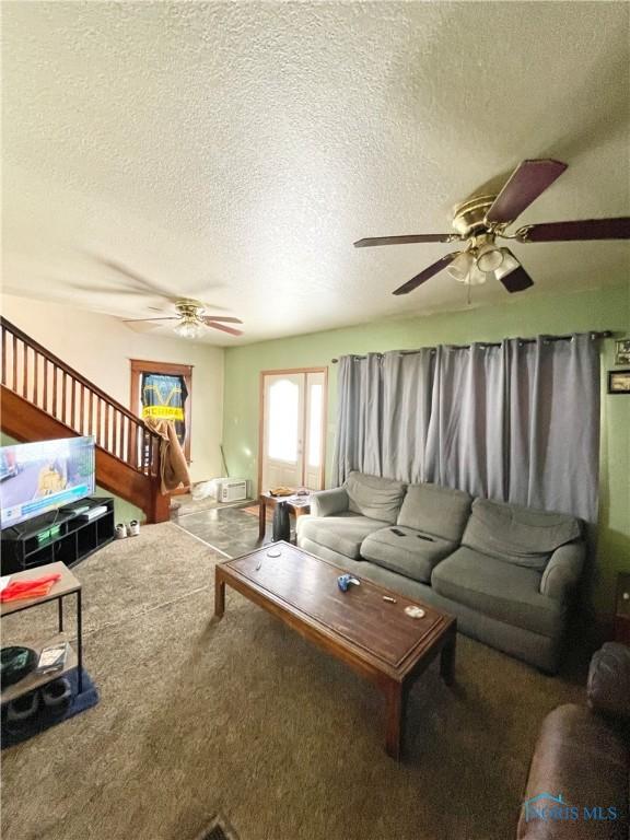 living room featuring ceiling fan, carpet, and a textured ceiling