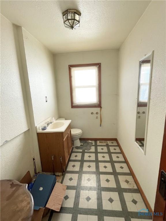 bathroom with vanity, a textured ceiling, and toilet