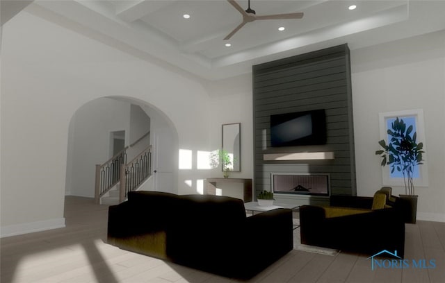 living room with a fireplace, light wood-type flooring, coffered ceiling, ceiling fan, and beam ceiling