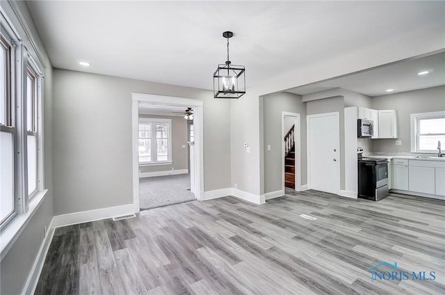 unfurnished dining area with sink, an inviting chandelier, and light wood-type flooring