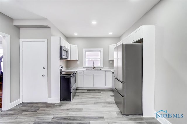 kitchen with white cabinetry, appliances with stainless steel finishes, light hardwood / wood-style floors, and sink