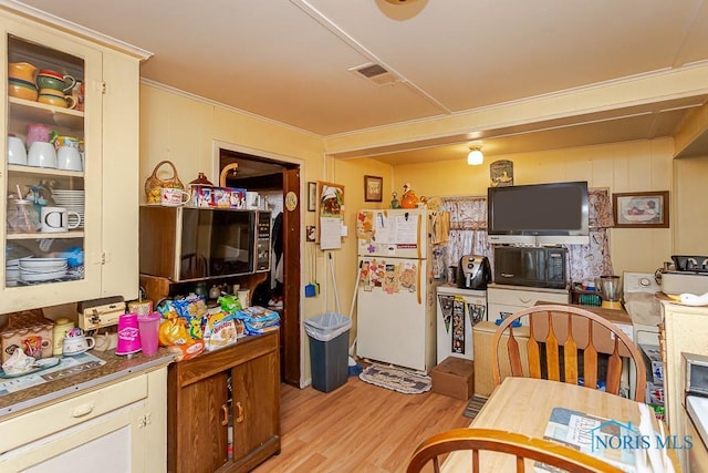 kitchen featuring visible vents, black microwave, light wood finished floors, and freestanding refrigerator