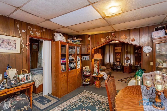 dining area featuring wood walls and a paneled ceiling