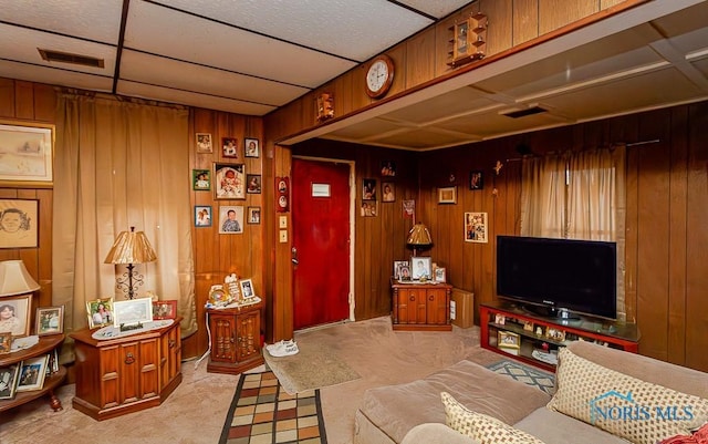 living room with carpet floors, a paneled ceiling, wood walls, and visible vents