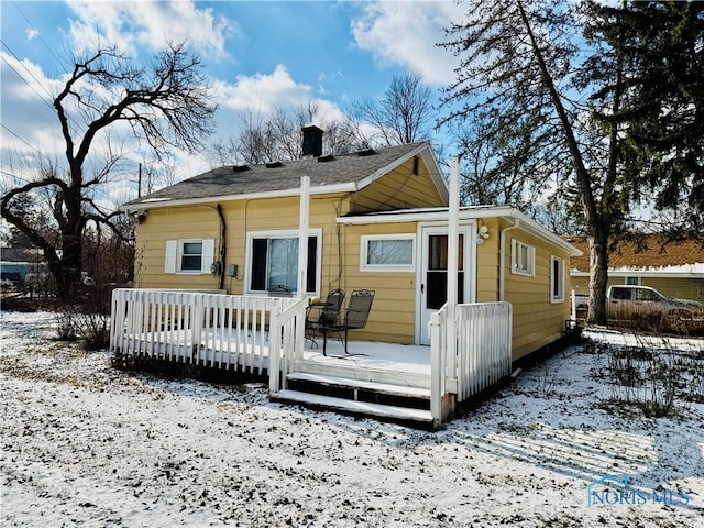 snow covered rear of property with a wooden deck