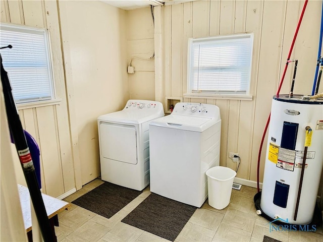 laundry room with washer and dryer, water heater, and wood walls