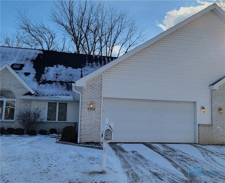 snow covered property with a garage