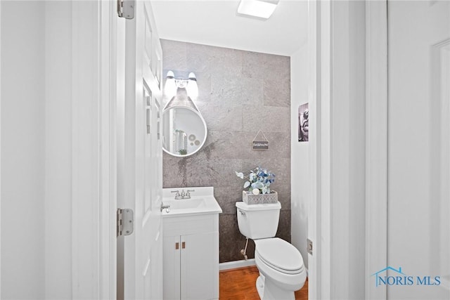 bathroom featuring hardwood / wood-style flooring, vanity, tile walls, and toilet