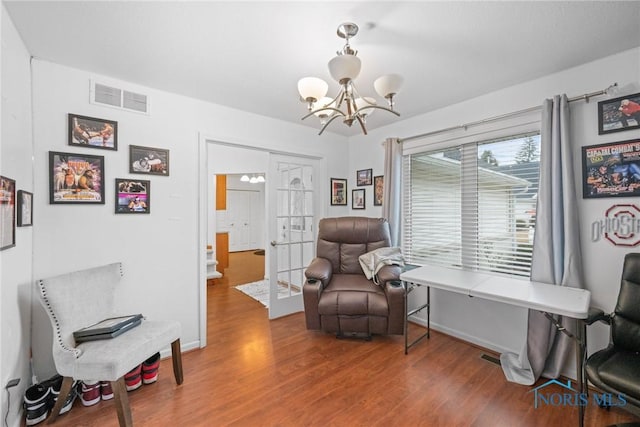 sitting room with hardwood / wood-style flooring, an inviting chandelier, and french doors