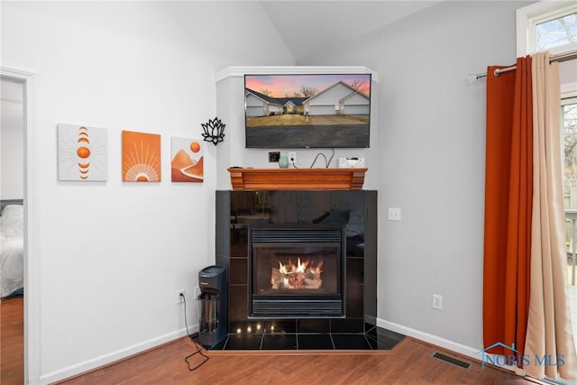 room details featuring a tile fireplace and wood-type flooring