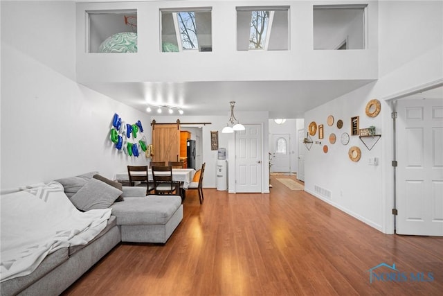 living room with a barn door, a towering ceiling, and hardwood / wood-style floors