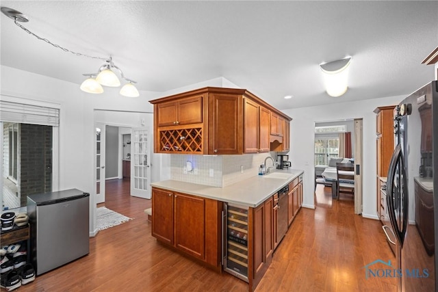 kitchen with tasteful backsplash, appliances with stainless steel finishes, beverage cooler, and wood-type flooring