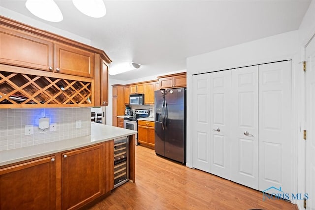 kitchen with tasteful backsplash, light hardwood / wood-style flooring, beverage cooler, and appliances with stainless steel finishes