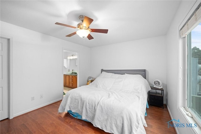 bedroom with dark wood-type flooring, ceiling fan, and ensuite bath