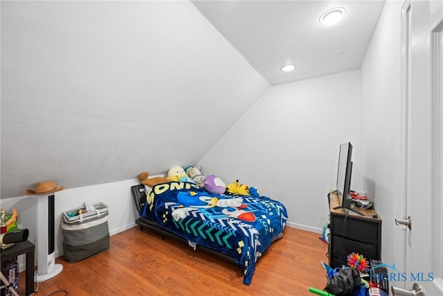 bedroom featuring hardwood / wood-style flooring and lofted ceiling