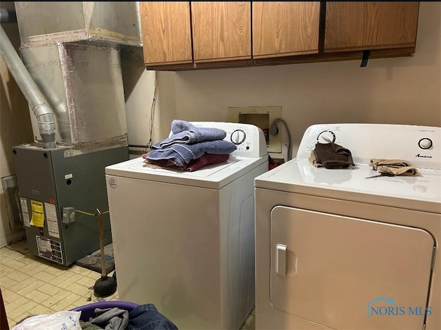 laundry area with heating unit, washing machine and dryer, and cabinets