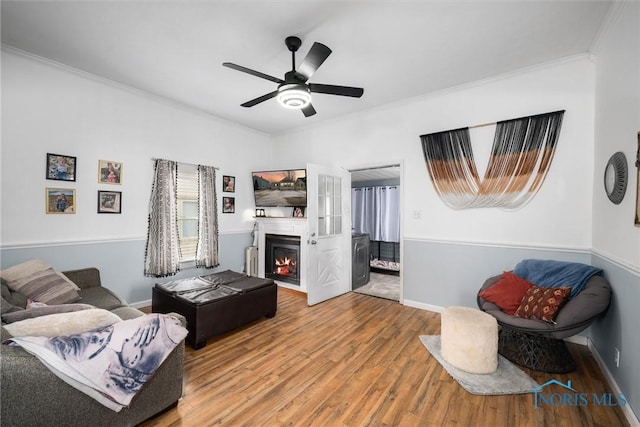 living room with wood-type flooring, ornamental molding, and ceiling fan