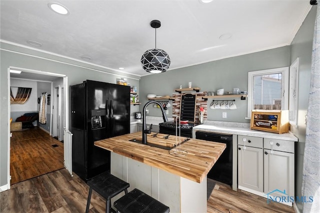 kitchen with sink, dark hardwood / wood-style flooring, hanging light fixtures, black appliances, and wood counters