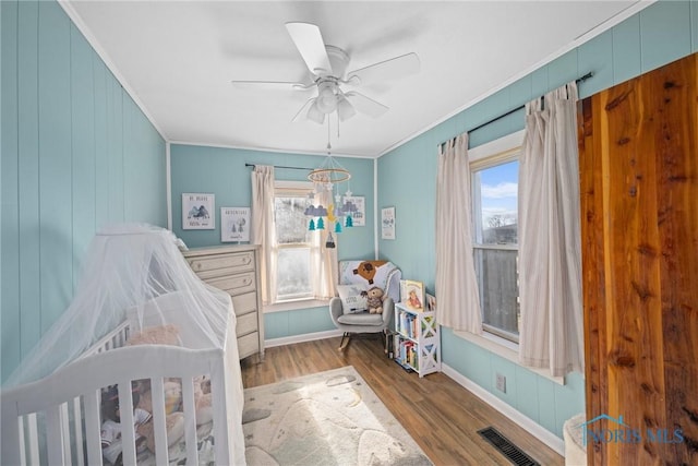 bedroom with ceiling fan with notable chandelier, ornamental molding, and light hardwood / wood-style floors