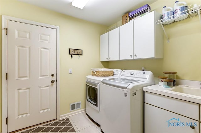 clothes washing area with independent washer and dryer, cabinets, sink, and light tile patterned floors