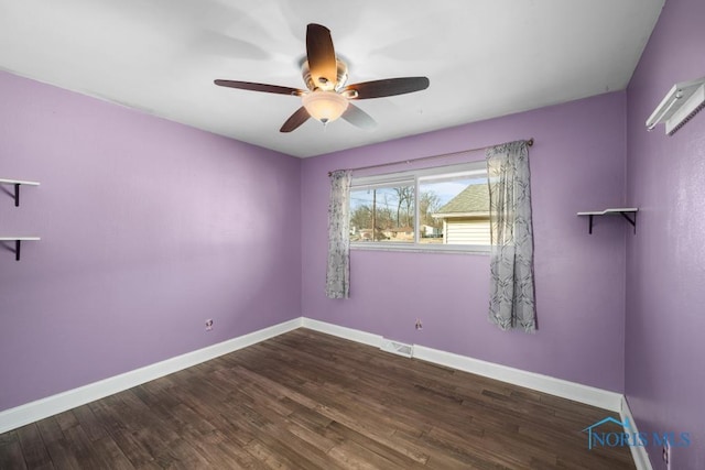 spare room with dark wood-type flooring and ceiling fan