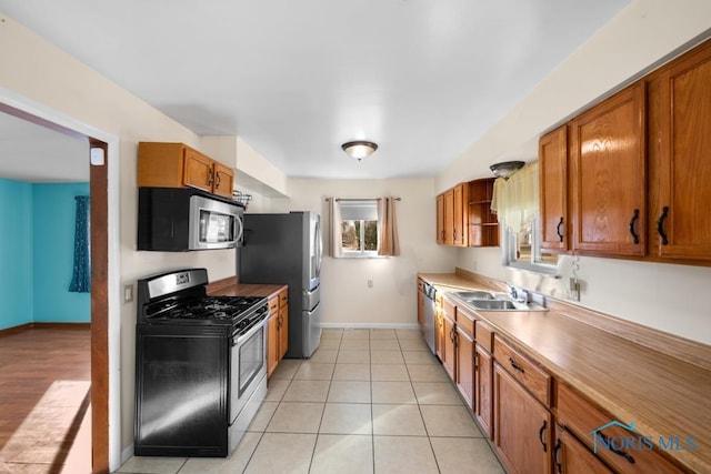 kitchen featuring light tile patterned flooring, appliances with stainless steel finishes, and sink