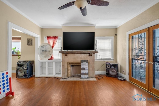 unfurnished living room featuring hardwood / wood-style flooring, ornamental molding, french doors, and a tile fireplace