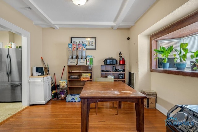 dining space with beam ceiling and light wood-type flooring