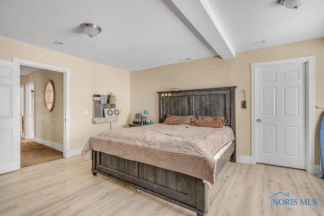 bedroom featuring light hardwood / wood-style floors and beamed ceiling