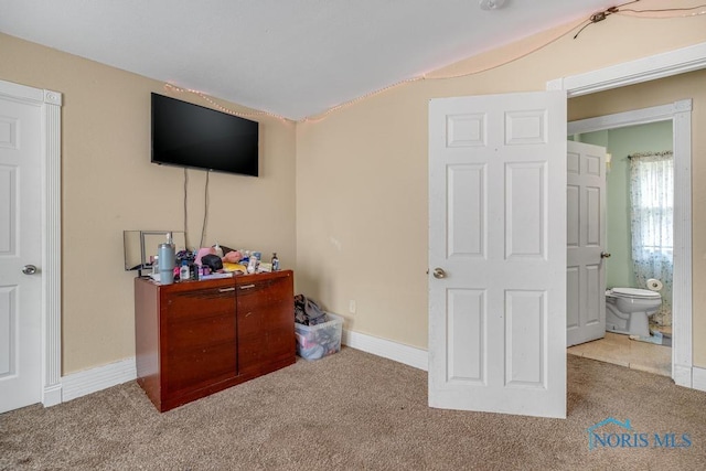 bedroom featuring ensuite bath and light colored carpet