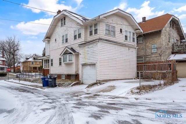 snow covered house featuring a garage