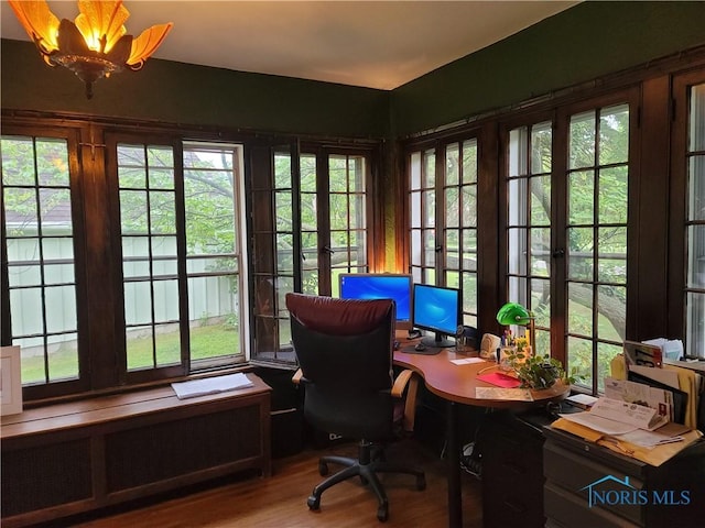 home office featuring wood-type flooring, radiator, a wealth of natural light, and an inviting chandelier