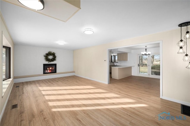 unfurnished living room with a notable chandelier and light hardwood / wood-style flooring