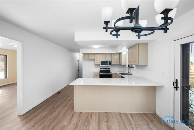 kitchen featuring sink, a notable chandelier, kitchen peninsula, stainless steel appliances, and light hardwood / wood-style flooring