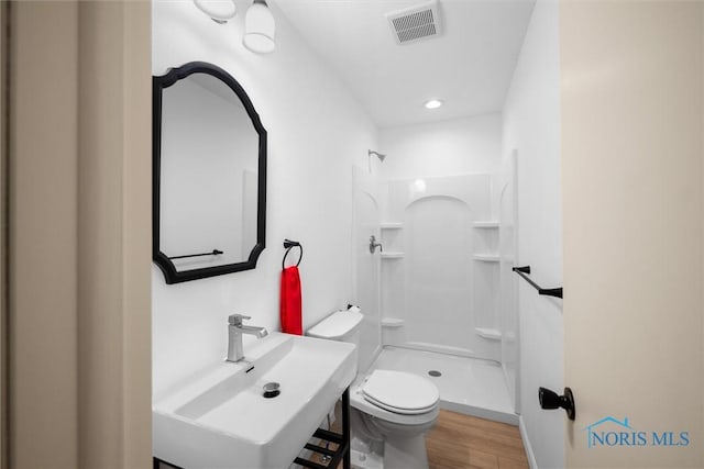 bathroom featuring walk in shower, wood-type flooring, toilet, and sink